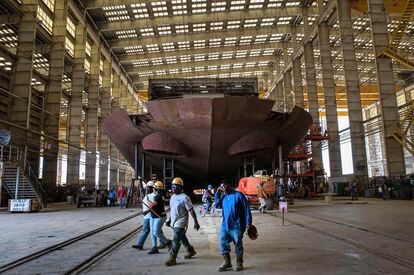 Workers pass the stern of the unfinished 260-foot-long Eco Edison ship in Terrebonne Parish, Louisiana, along the Houma Navigation Canal, on April 3, 2023.