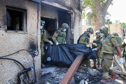 Israeli soldiers remove the body of a compatriot, killed during an attack by the Palestinian militants, in Kfar Aza, south of Israel bordering Gaza Strip, on October 10, 2023. 
