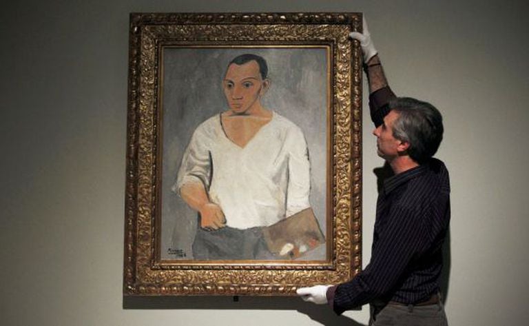 A gallery employee adjusts Picasso's 'Self-portrait with palette' at the Fundación Mapfre exhibition in Madrid.