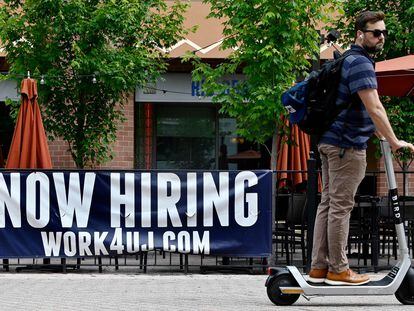 A man passes in front of a "now hiring" sign posted outside a restaurant in Arlington, Virginia, in June 2022.