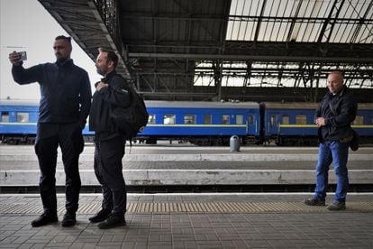 Watched by one of his bodyguards, Kamishin (left) attends a video call at Lviv train station with Oleksandr Pertsovskii, the company's passenger transport manager.