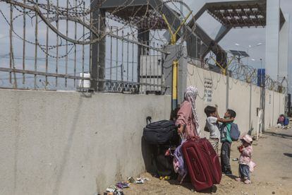 A woman and three children wait next to the border wall for the Rafah crossing to open on October 16.
