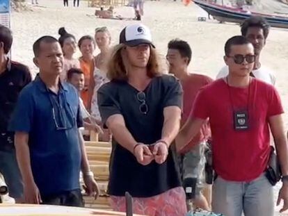 Daniel Sancho, wearing a cap and handcuffed, surrounded by Thai police officers after his arrest on the island of Koh Pha-ngan.