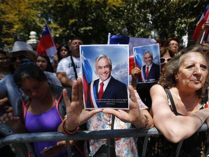 A woman holds a photograph of Sebastián Piñera as she waits for the arrival of his coffin in front of the Old Congress, in Santiago, on Wednesday, February 7.