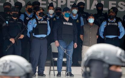 Former Honduran President Juan Orlando Hernandez, center in chains, is shown to the press in Tegucigalpa.