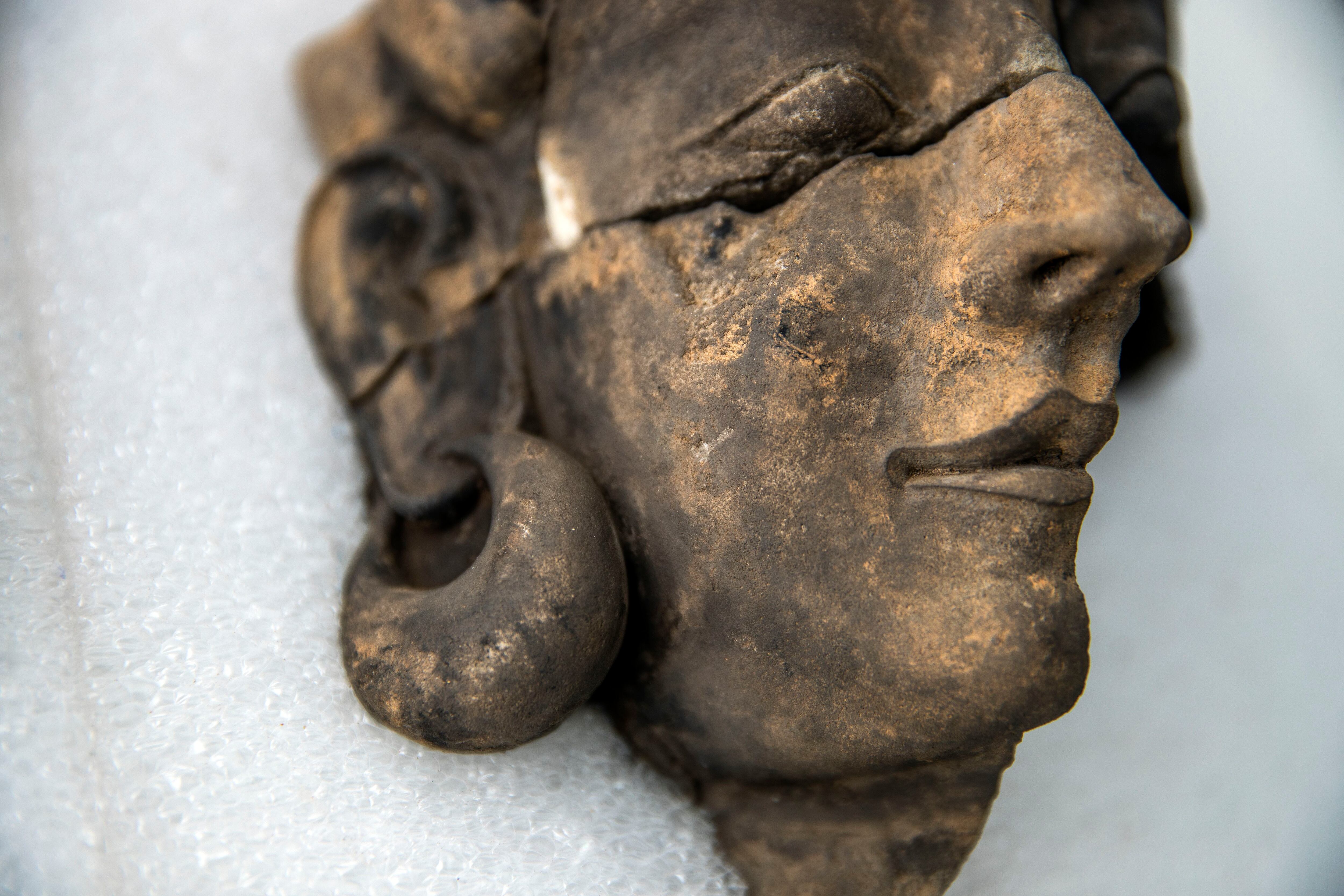 Detalle del pendiente de oro hueco del busto ennegrecido por el fuego. 