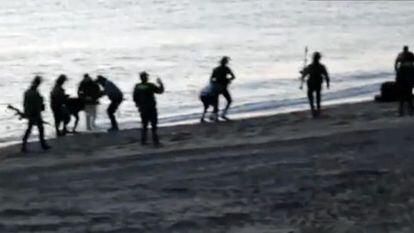 Civil Guard officers returning migrants to Morocco at Tarajal beach.