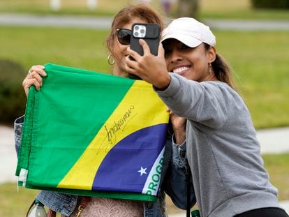 Supporters of former Brazilian president Jair Bolsonaro take a selfie with a flag that Bolsonaro autographed outside the home where he is living Friday, Jan. 13, 2023, in Kissimmee, Fla.