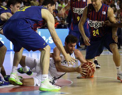 Real Madrid forward Rudy Fern&aacute;ndez (c) fights for the ball among FC Barcelona players during the fourth game of the final series.