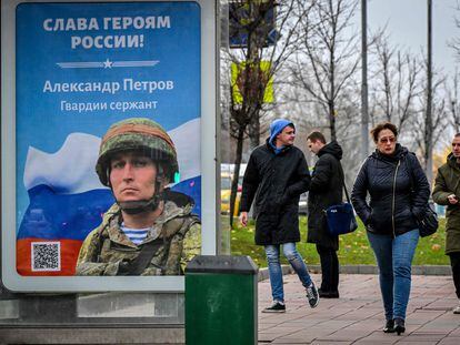 People walk past a Moscow poster that reads 'Glory to the Heroes of Russia' on Monday October 24, 2022.