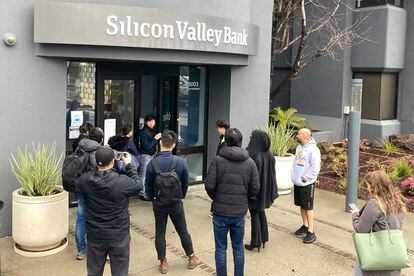 A person from inside Silicon Valley Bank, middle rear, talks to people waiting outside of an entrance to Silicon Valley Bank in Santa Clara, Calif., Friday, March 10, 2023.