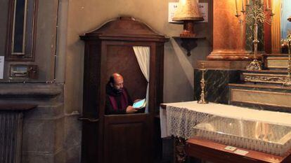 A priest uses his iPad in the church’s confessional, located next to one of the four TV screens that have been installed in the church.