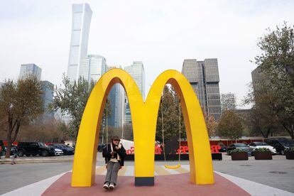 A woman sits on a swing attached to a giant sign of McDonald's, outside its themed exhibition in Beijing, China December 4, 2023