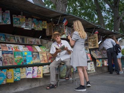 Alain Papillaud talks to a tourist at his bookstand.