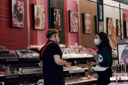 A worker, at left, tends to a customer at a cosmetics shop on Thursday, May 20, 2021