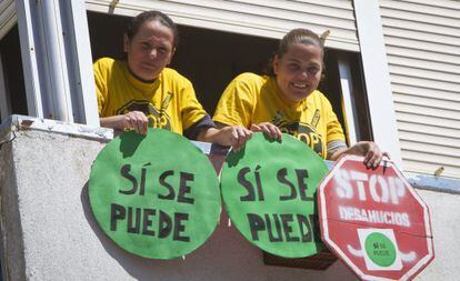 The Huelva woman saved from eviction, Mar&iacute;a del Carmen And&uacute;jar Hidalgo (l), and her sister hang placards from the window of the embargoed flat.