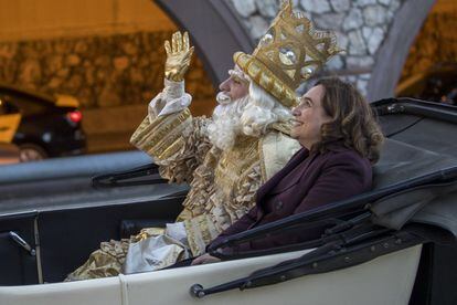 The mayor of Barcelona, Ada Colau, sits in a carriage alongside King Melchior in a parade through the streets of Barcelona.
