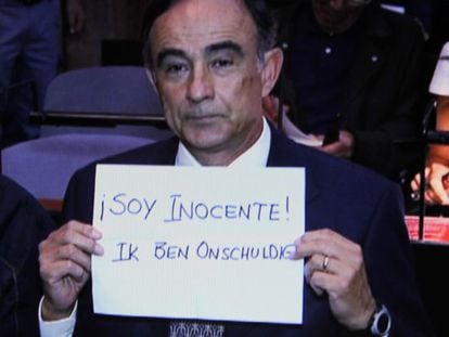 Julio Alberto Poch, a former pilot for the Dutch airline Transavia, holds up a sign protesting his innocence.