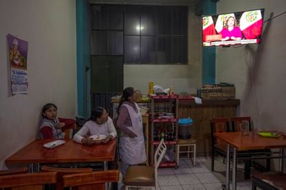 Women watching Peruvian President Dina Boluarte's message to the nation, inside a restaurant in Juliana on Sunday.