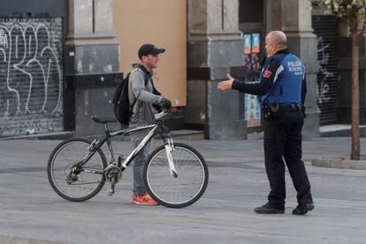 A Madrid local police officer tells a member of public that he cannot ride his bicycle under the state of alarm decreed in Spain on Saturday.