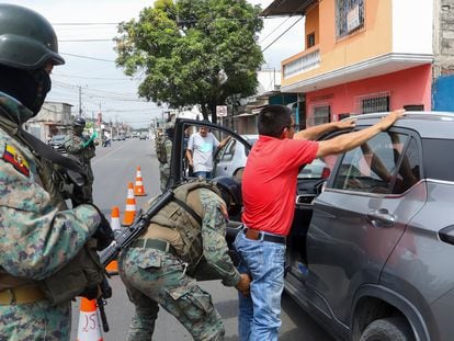 A soldier pats down a driver at a road block in Guayaquil, Ecuador, Thursday, Aug. 10, after President Guillermo Lasso declared a state of emergency.