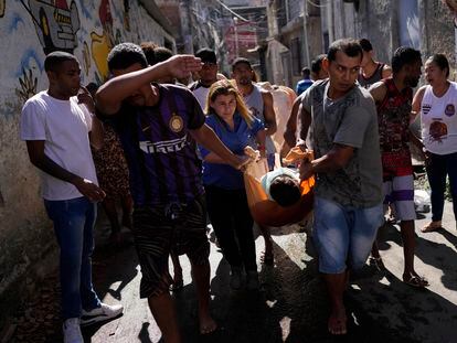 People carrying a dead body following a police raid in a favela complex in the north of Rio de Janeiro (Brazil).