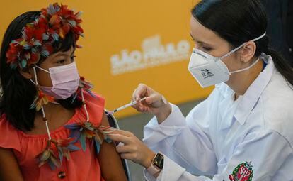 A health worker gives a shot of the Pfizer COVID-19 vaccine to 9-year-old Indigenous youth