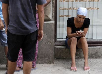 A woman uses a cellphone on a street in Havana.