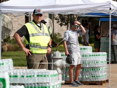 People stand by cases of bottled water as the City of Germantown gives them out to residents on July 24, 2023, at Forest Hill Elementary School in Germantown, Tennessee.