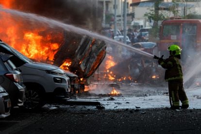 A firefighter extinguishes burning vehicles following a Palestinian attack on Ashkelon.