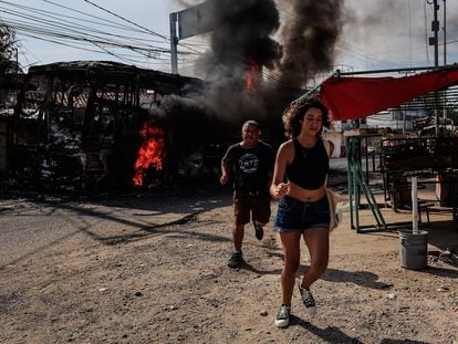 Passers-by run past a truck that was set on fire in Acapulco.