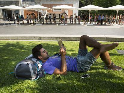 A tourist takes a break while people stand in line outside the Prado museum.