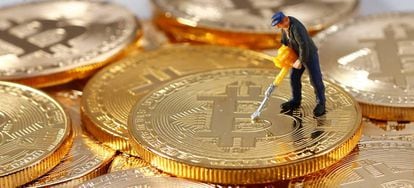 Uma figura em miniatura em cima de uma pilha de moedas representando bitcoins.