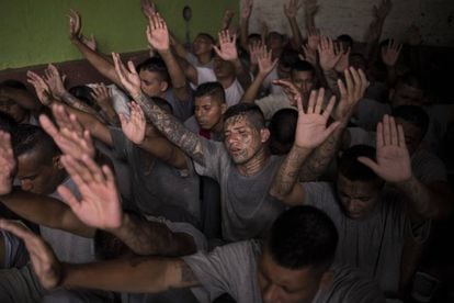 Former gang members, in San Francisco Gotera prison, raise their hands during a religious ceremony.