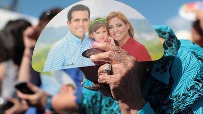 A woman shields herself from the sun using Rosselló campaign material.