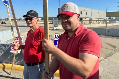 Striking United Auto Workers member Chris Jedrzejek, right, and his father picket outside Ford Motor Co.'s Michigan Assembly Plant Monday, Oct. 2, 2023