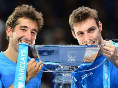 Spain&#039;s Marcel Granollers (R) and Spain&#039;s Marc Lopez (L) bite the cup as they celebrate winning the doubles final at the ATP World Tour Finals. 