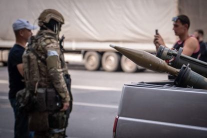 Two Rostov residents take a photograph with a Wagner member. In the foreground, two grenade launchers on a vehicle.