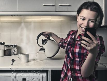 Woman in kitchen cooking and looking at her phone