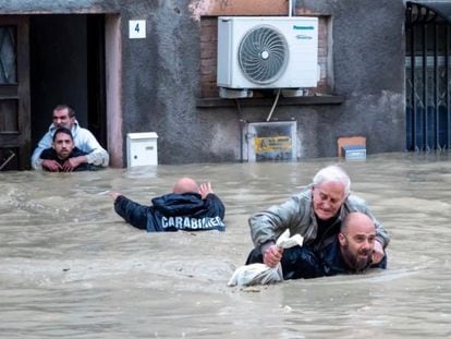 Members of the national gendarmerie of Italy carry residents piggyback through the flooded streets.
