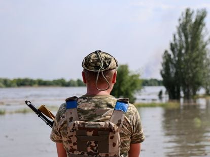 A Ukrainian soldier stands on a street flooded by the ruptured Nova Kakhovka dam in Kherson on May 6, 2023.