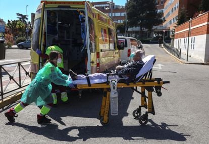 A healthcare worker wearing a protective face mask and suit transports a patient from an ambulance to the emergency unit at 12 de Octubre hospital during the coronavirus disease (COVID-19) outbreak in Madrid, Spain March 28, 2020. REUTERS/Sergio Perez