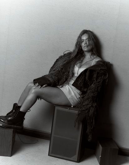 Karol G, wearing a jacket from Javier Guijarro, a top from Sehnsucht Atelier, GCDS jeans and Doc Martens boots