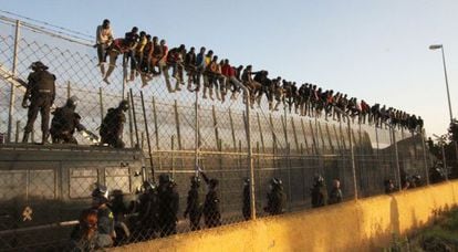 Dozens of migrants atop the Melilla border fence.