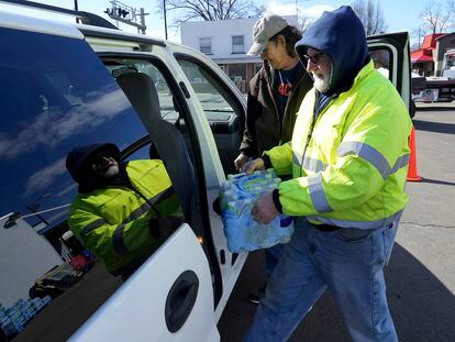 Volunteer Larry Culler helps load water into a car in East Palestine, Ohio, as cleanup from the Feb. 3 Norfolk Southern train derailment continues, Friday, Feb. 24, 2023.