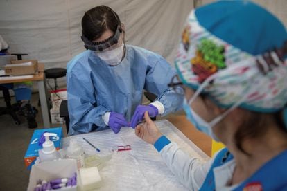 A health worker performs a fast coronavirus test on an emergency worker in Madrid.