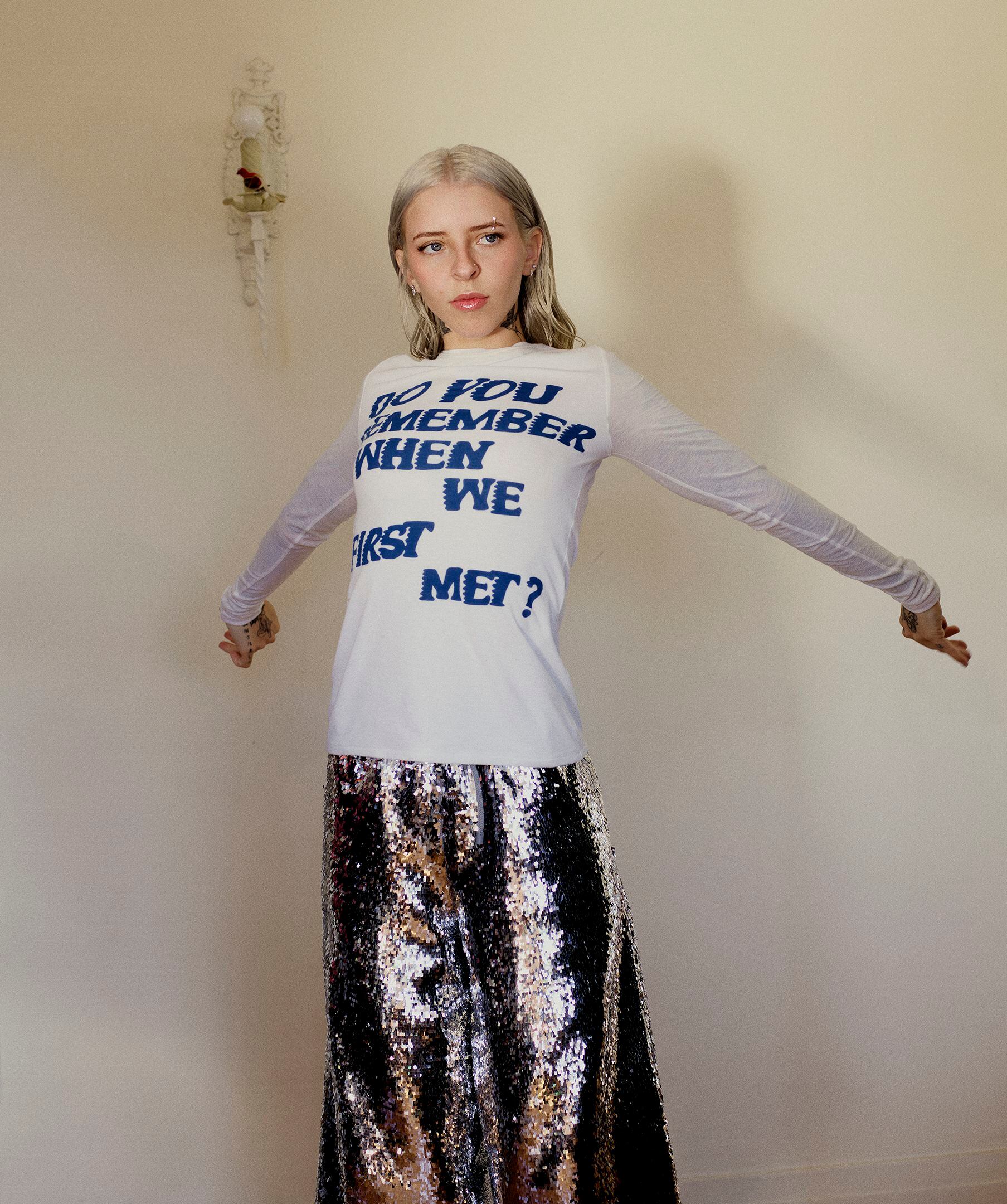 The artist wears LOEWE Paula's Ibiza woven-letter T-shirt and sequined skirt. 