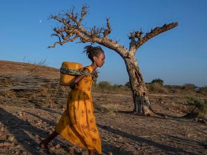 A young woman who fled the conflict in Ethiopia's Tigray region carries water at Umm Rakouba refugee camp in Qadarif, eastern Sudan.