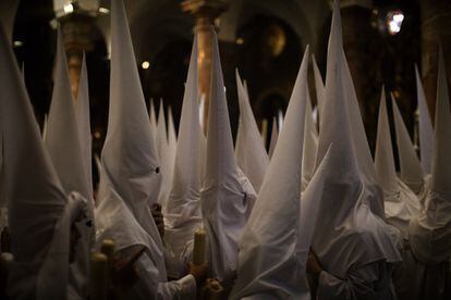 Penitents of the La Candelaria brotherhood prepare in church to participate in a procession in Seville on April 16, 2019.