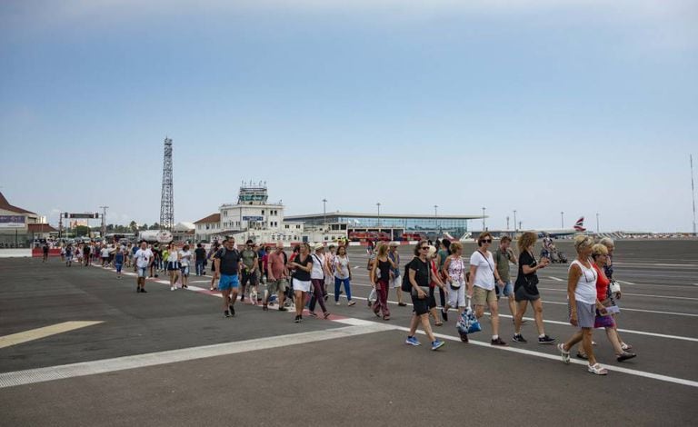 People cross a runway into Gibraltar.